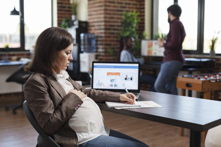 Pregnant woman analyzing economic growth of company and reviews financial and management chart Pregnant woman analyzing economic growth of company and reviews financial and management chart